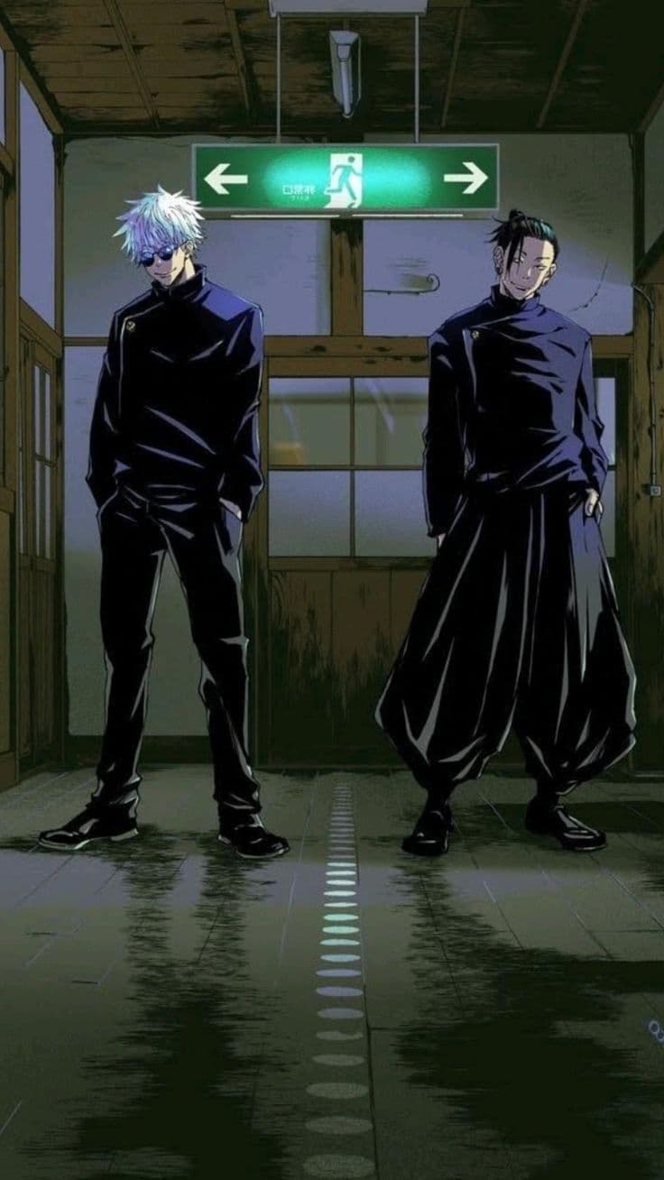 The image features two male characters, Satoru Gojo and Suguru Geto, standing side-by-side in a dimly lit hallway. Both are dressed in their dark, high-collared Jujutsu High school uniforms; Gojo on the left wears slim-fit trousers and dark sunglasses, while Geto on the right wears wide-legged hakama-style pants with his hair in a half-up bun. They are depicted in a confident, upright standing pose with hands in their pockets, looking directly toward the viewer with slight smiles. The setting appears to be an old wooden school corridor, characterized by a glowing green emergency exit sign hanging above them and a reflective, polished floor. The artistic style utilizes sharp line work and heavy cel-shading, creating deep shadows that contrast with the bright green light source. The overall atmosphere is cool, nostalgic, and slightly mysterious, capturing a moment of camaraderie between the two protagonists.