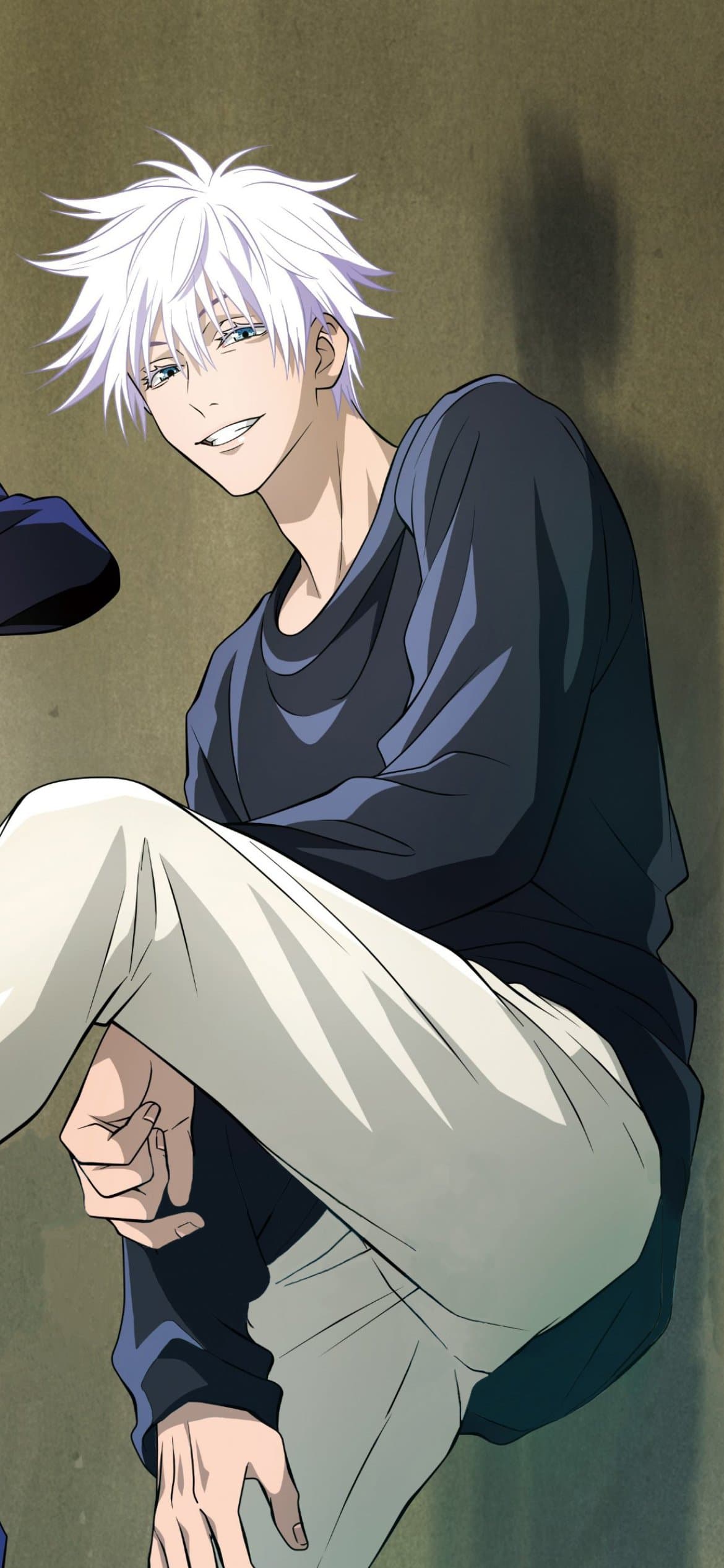 The image features Satoru Gojo from Jujutsu Kaisen, depicted with his signature spiky white hair and striking blue eyes. He is dressed in casual, modest attire consisting of a long-sleeved dark navy blue shirt and loose-fitting light cream or white trousers. The character is shown in a relaxed, seated pose leaning against a textured, olive-toned wall, looking directly at the viewer with a confident and playful smirk. The artistic style is characteristic of modern high-quality TV anime, utilizing clean line work and precise cel-shading to define the folds in his clothing and the anatomy of his neck and hands. The lighting is soft and natural, coming from the front-left, which creates gentle shadows that add depth to the composition. The overall atmosphere is peaceful and charismatic, capturing a rare moment of casual downtime for the powerful sorcerer.